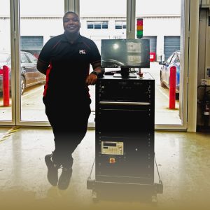 Nigel Mungombe standing next to his first system build as an MK Test Systems employee
